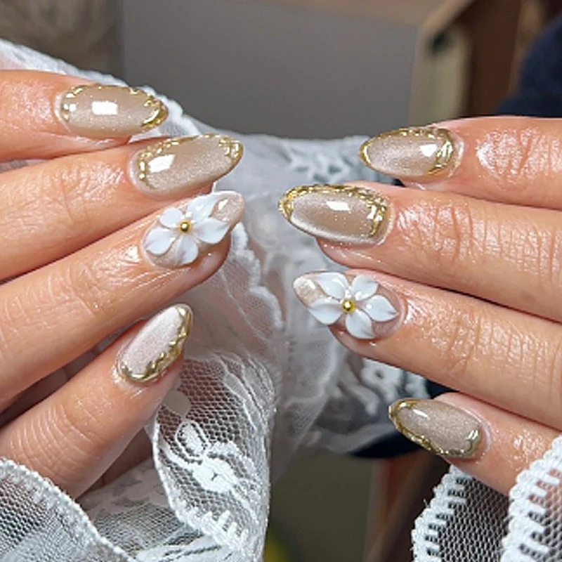 Kunstnagelset mit eleganten Goldverzierungen und floralem Akzent Karnz