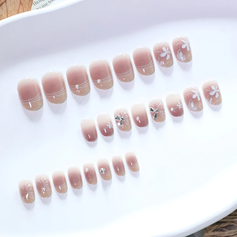 Kunstvolle Nagelgestaltung mit floralem Design und Glitzerakzenten Karnz