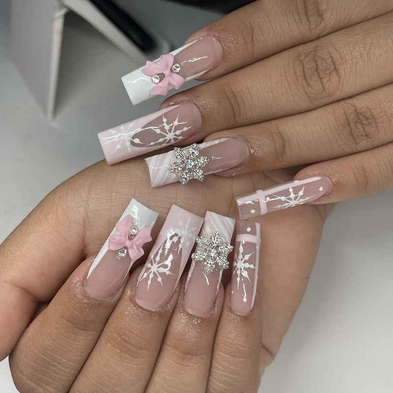Kreatives Kunstnagelset mit filigranen Schneeflocken- und Schleifenverzierungen Karnz