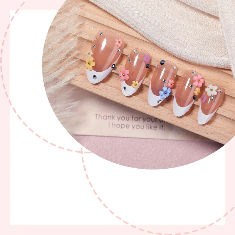 Kunstnagelset mit zarten Blumenverzierungen und funkelnden Strasssteinen Karnz